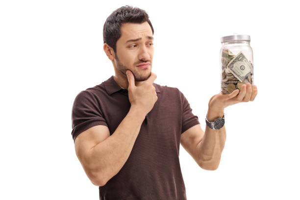 istock Pensive man looking at a jar filled with money 646489750