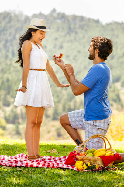 istock Boyfriend proposing and giving engagement ring at meadow 646499096