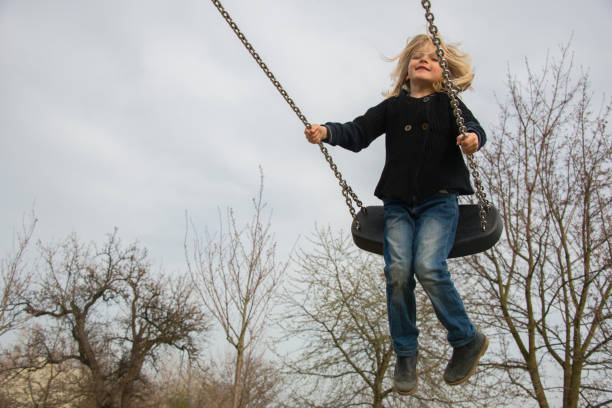 istock Little child blond girl having fun on a swing 646514936