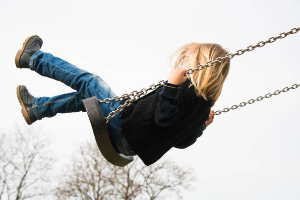 istock Little child blond girl having fun on a swing 646516064