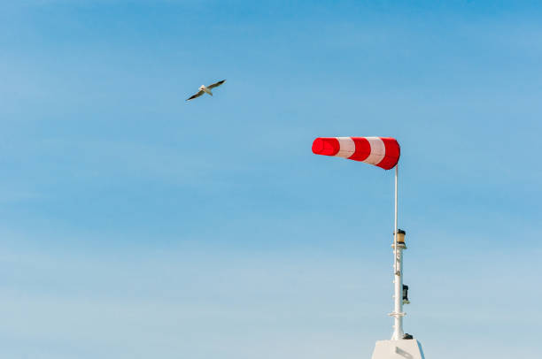 Red and white color striped windsock blowing in wind with mountains in background in Tromso - Norway