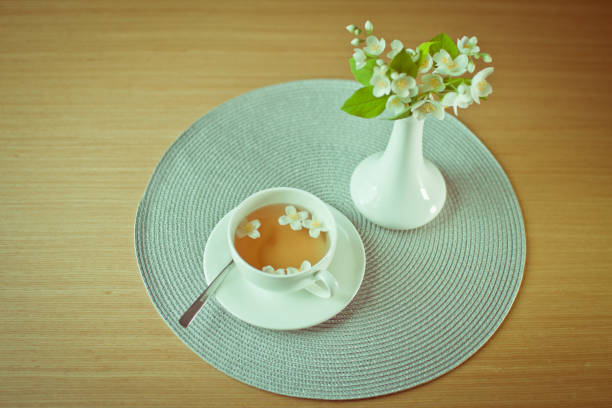 Jasmine green tea on a table in a white mug and a bouquet of spring flowers jasmine