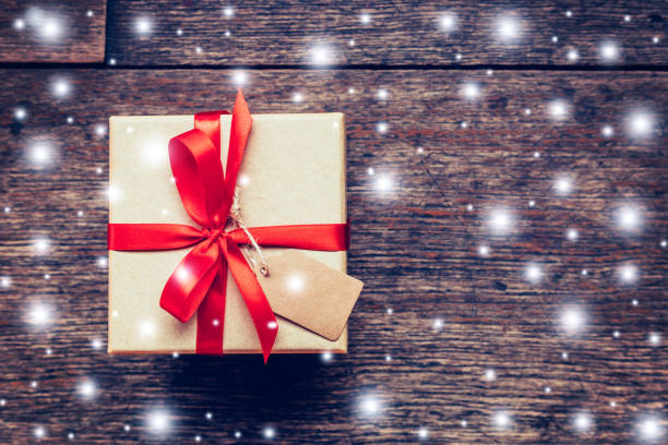 istock Gift box and red Ribbon, Snow with tag on wood. 646541304