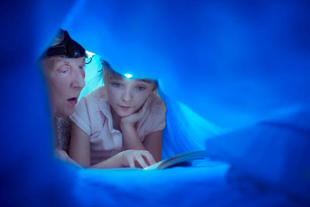 gran with a headtorch bedtime story - grandparent reading grandmother child imagens e fotografias de stock