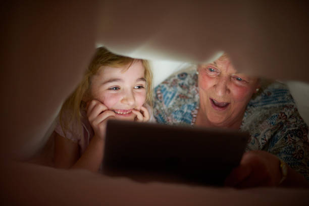 little girl reading to her grandmother . - grandparent reading grandmother child imagens e fotografias de stock