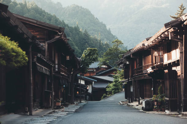 Japanese Village with Ryokan houses On a sunny day on the Nakasendo trail, the pathway connecting Kyoto and Tokyo in Japan a travelling man is hiking with a backpack and embracing both the nature and culture of this beautiful Edo period rural environment. country inn stock pictures, royalty-free photos & images
