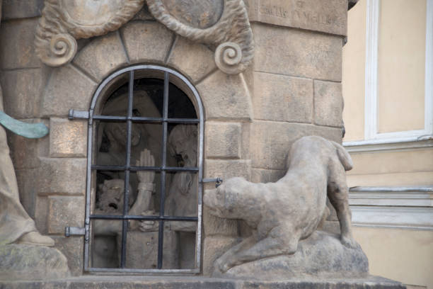 An old dog statue on the top of a column with a warehouse wall as a background