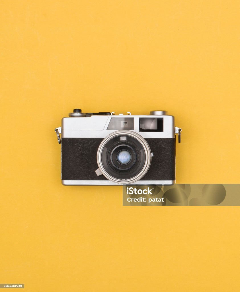 retro photography camera front view of old fashioned eighties camera on yellow background. Camera - Photographic Equipment Stock Photo