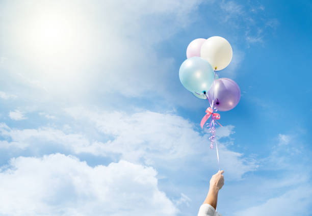 Girl hand holding multicolored balloons done with a retro vintage instagram filter effect, concept of happy birth day in summer and wedding honeymoon party (Vintage color tone)