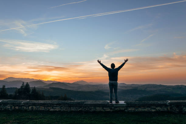 istock Young man with arms raised at sunset 646677392