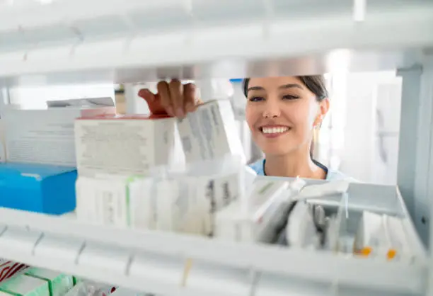 Portrait of a happy Latin American pharmacist selling prescribed medications at the hospital