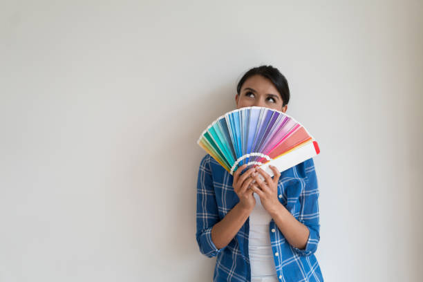 thoughtful woman thinking about the color of her house - home addition home improvement paint decorating imagens e fotografias de stock