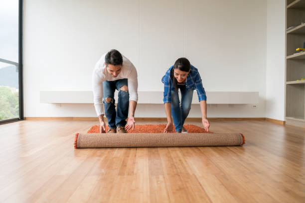 Couple moving house Couple moving house and unrolling the carpet at their new place - real estate concepts decorating stock pictures, royalty-free photos & images