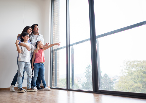 Portrait of a happy Latin American family looking at the view of their new house and smiling