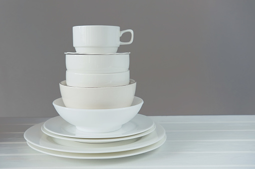Minimalist picture of white porcelain kitchenware made of different size and shape plate and bowls piled up