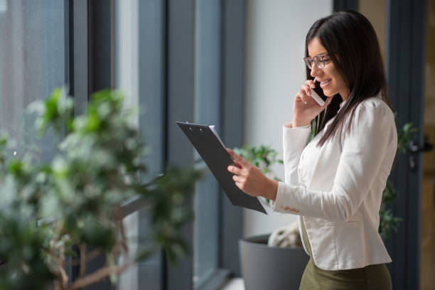 istock Young businesswoman talking on phone and looking at documents 646706380