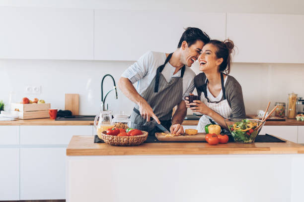 joven pareja en el amor en la cocina - cocinar fotografías e imágenes de stock