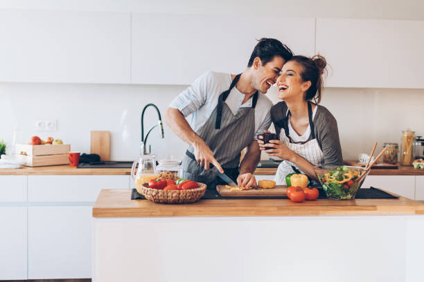 Young couple in love in the kitchen Affectionate couple preparing salad in a domestic kitchen date night romance stock pictures, royalty-free photos & images