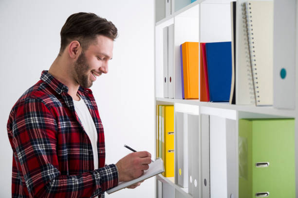 istock Side view of a cheerful man in a library writing 646730544