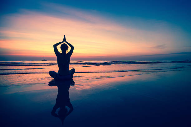 istock Silhouette young woman practicing yoga on the beach at surrealistic sunset. 646747176