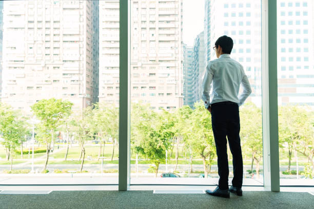 istock Thinking businessman in the office looking through the window 646753656