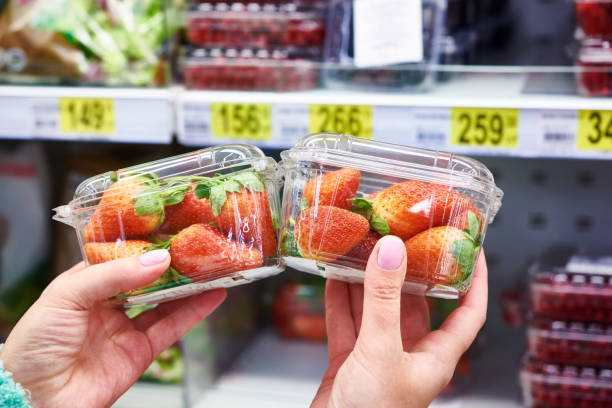 Strawberries in hands of buyer at store Strawberries in the hands of the buyer at the store on the background of shelves with products food fruit close up strawberry stock pictures, royalty-free photos & images