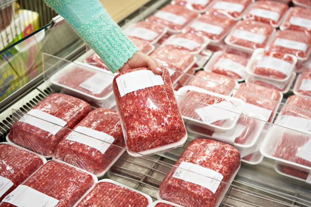 buyer woman chooses chopped meat in shop - ground beef imagens e fotografias de stock