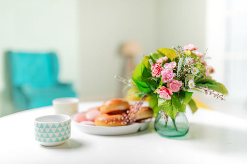 Soft and bright still life. Flowers in a vase, tea and a plate of tasty treats.