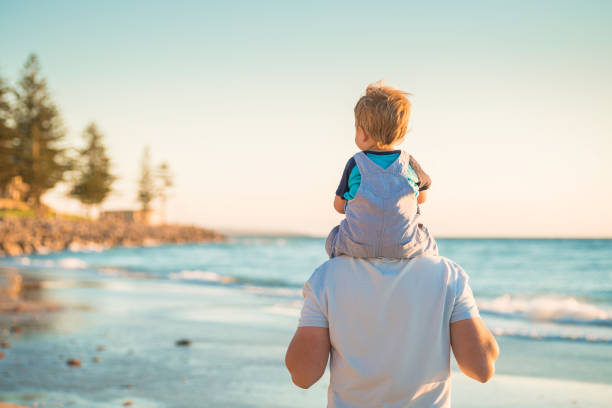 Father giving son piggyback ride on beach