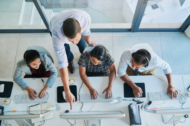 Quality customer service is a team effort High angle shot of a man assisting his colleagues in a call center service department stock pictures, royalty-free photos & images