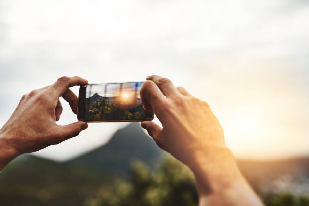 Cropped shot of a man taking a picture of the scenery at the top of a mountain