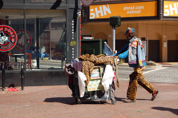 SAN FRANCISCO, USA - JUN 14, 2015: Homeless unknown adult in the streets. He pushes his belongings in a shopping cart in search of the next ratchet. The sun is shining and it is warm. Nevertheless, this does not seem to bother stock photo