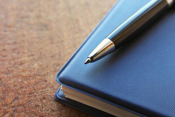 istock blue notebook and ball pen on wooden backgroundwith copy space. 646844456