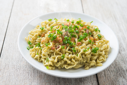 Plate of dried noodles on wooden table.