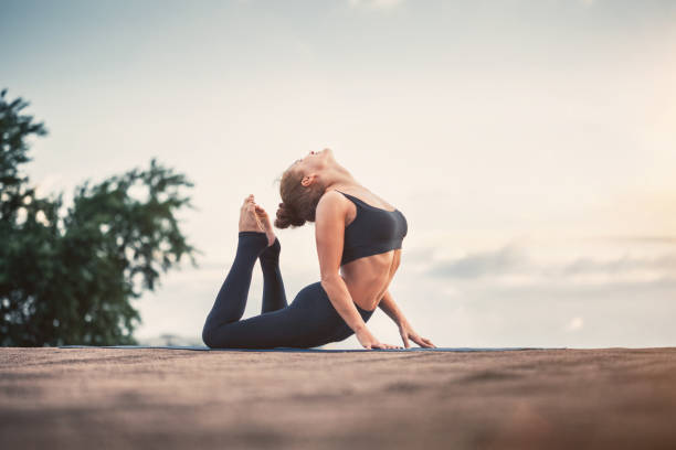istock Young woman doing yoga exercises at sunset 646852672