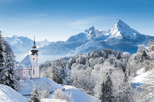 Panoramic view of beautiful winter wonderland mountain scenery in the Alps with pilgrimage church of Maria Gern and famous Watzmann summit in the background, Berchtesgadener Land, Bavaria, Germany