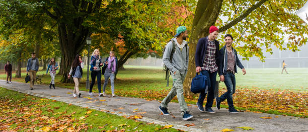 University students walking on footpath University students having fun while walking in campus. campus stock pictures, royalty-free photos & images