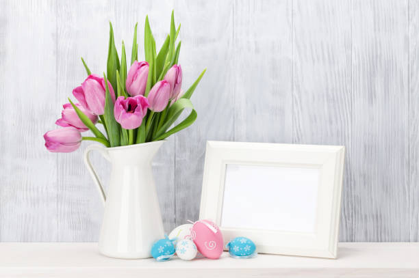 istock Easter eggs, photo frame and pink tulips 646869886