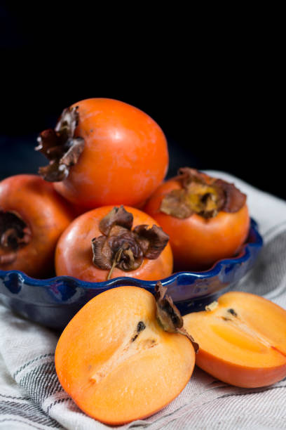 istock Ripe orange persimmons in blue bowl 646872590