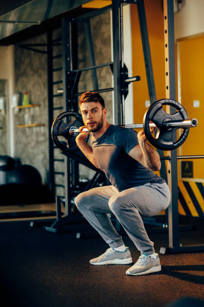 istock Handsome man doing squats with weights in the gym 646873236