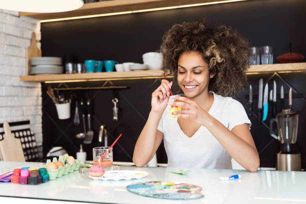 istock Beautiful African American woman coloring Easter eggs 646880822