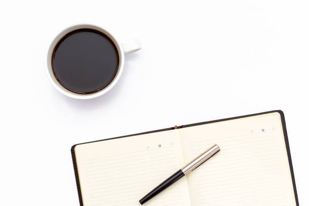 istock the black open diary, pen and a Cup of black coffee on white background 646881196