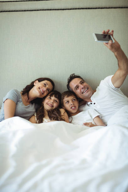 istock Parents and kids taking a selfie on bed 646885050