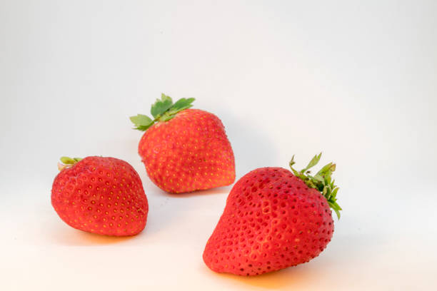 Three perfectly cleaned strawberries with leaves isolated on the white background