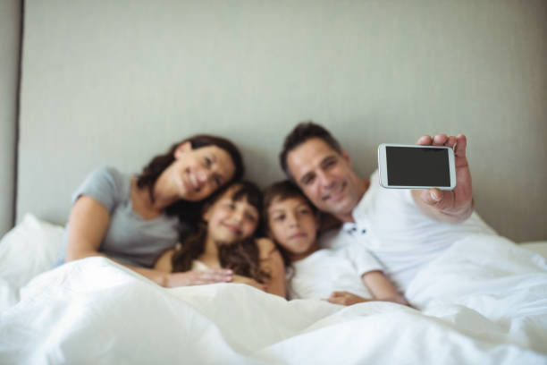 istock Parents and kids taking a selfie on bed 646885228