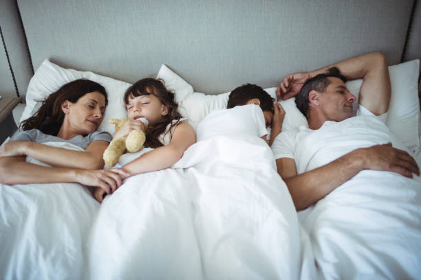 istock Parents and kids sleeping on bed 646891928