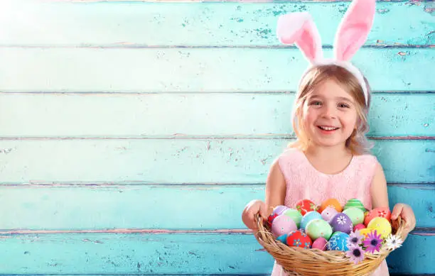 Easter - Little Girl With Basket Eggs And Bunny Ears And Blue Wooden Background
