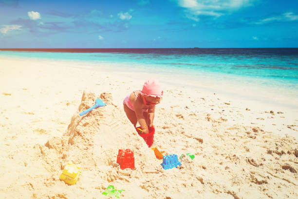 istock cute little girl play with sand on beach 646900022