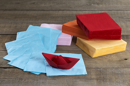 Paper napkins and paper boat on a wooden table