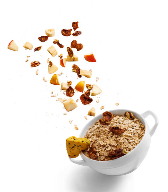 bowl of healthy oatmeal with falling fruit with the ingredients in the air - dried apple imagens e fotografias de stock